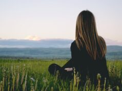 woman wearing black long sleeved shirt sitting on green grass field